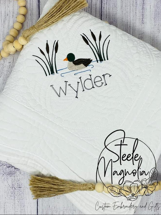 White baby quilt with duck design and embroidered name